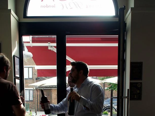 Un ospite degusta un calice sulla soglia del locale