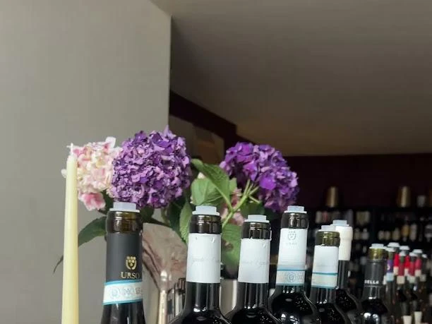 Bottiglie di Cantine Urso e composizione floreale sul banco