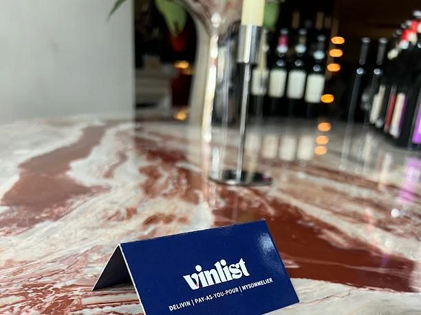 Il biglietto Vinlist accanto alle bottiglie sul tavolo di marmo
